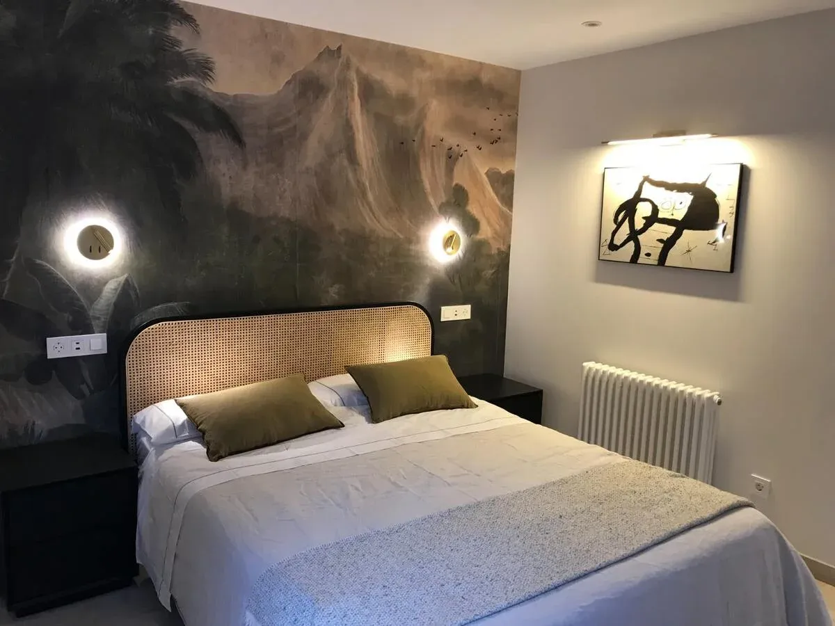 Dormitorio con papel pintado, cabecero de rejilla y apliques de pared