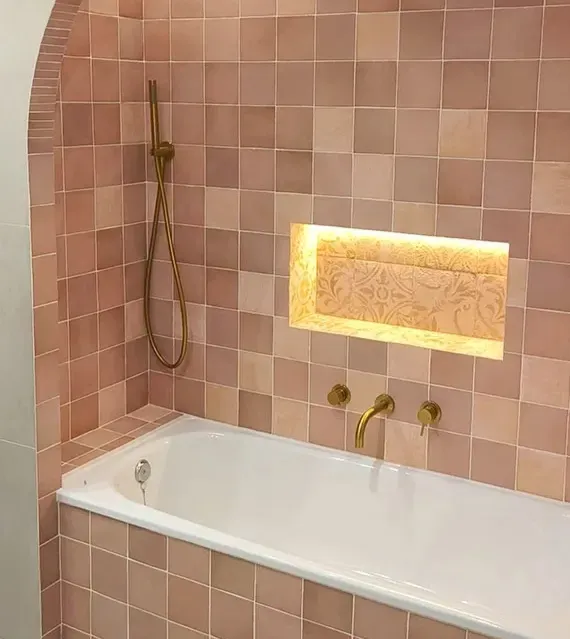 Baño del ático con cerámica rosa artesanal y hornacina iluminada