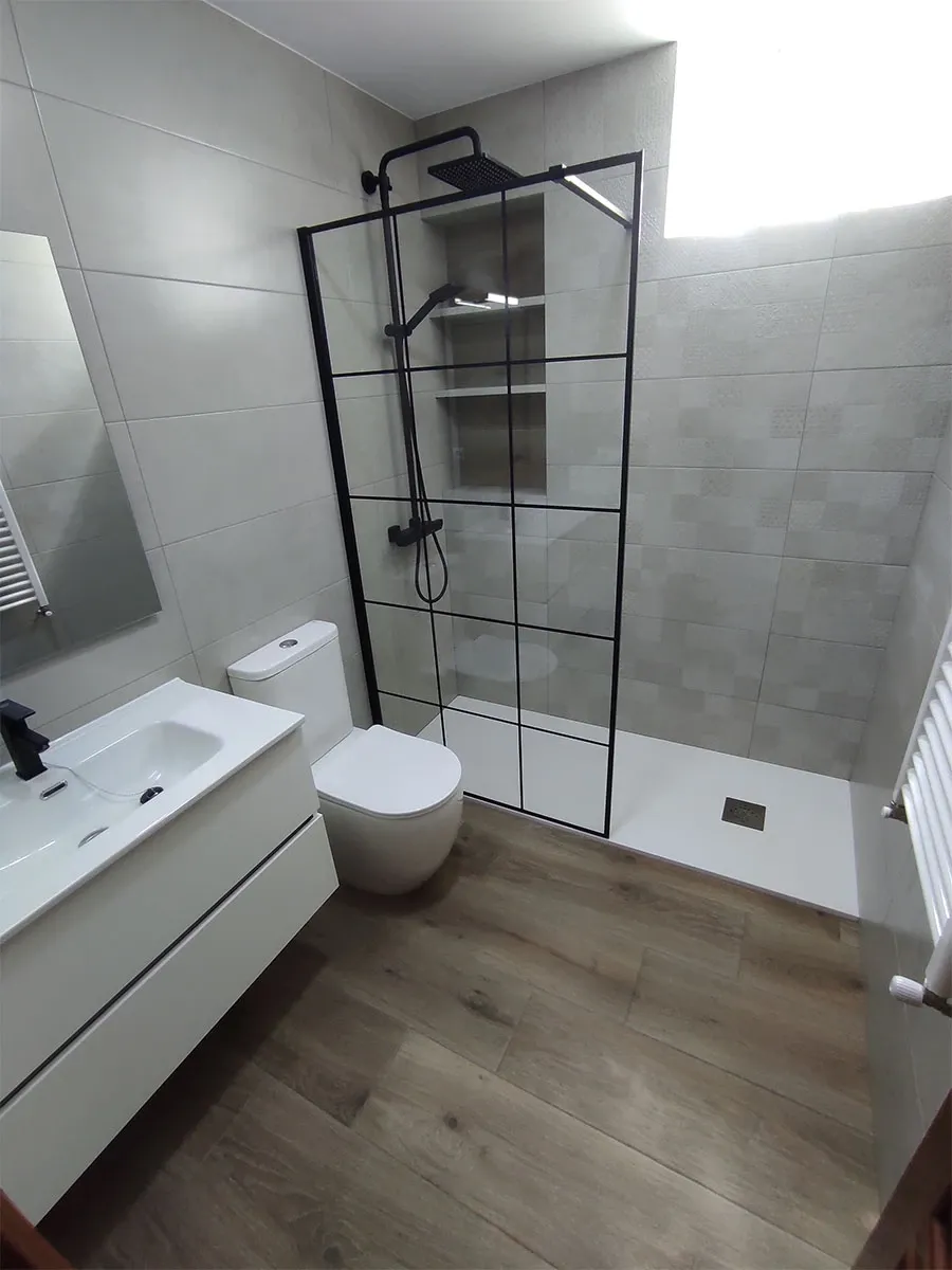 Baño con mampara negra de cuadrícula y suelo de imitación madera