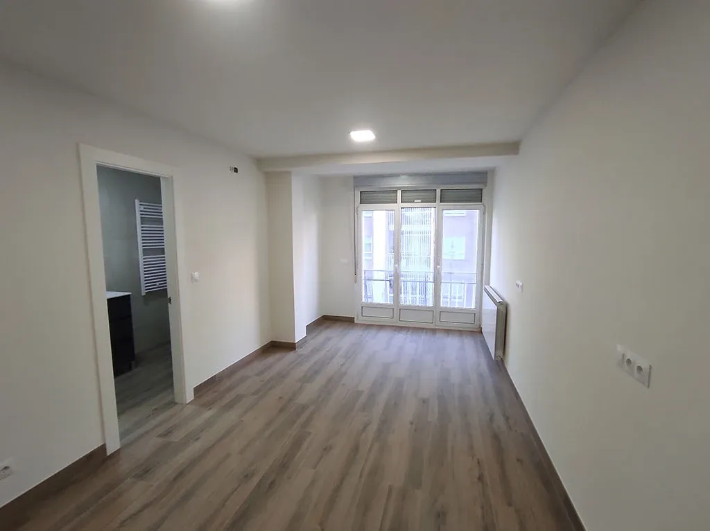 Salón y pasillo reformados con suelo de madera y paredes blancas