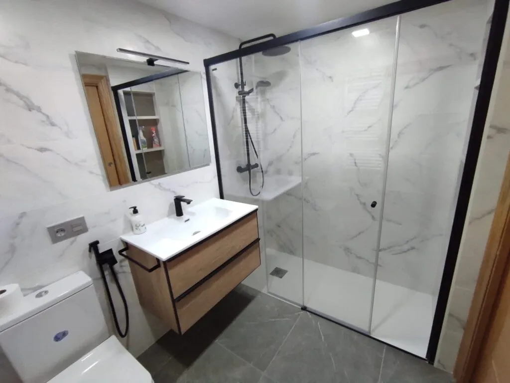 Baño nuevo con cerámica de imitación mármol y mampara negra